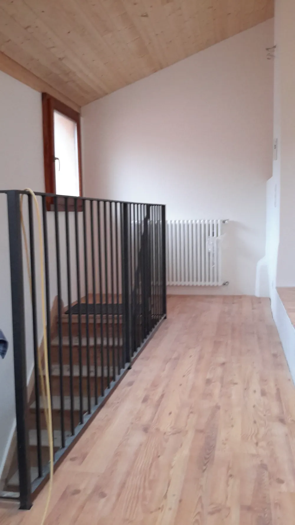 Interno ristrutturato con parquet e scala con ringhiera nera