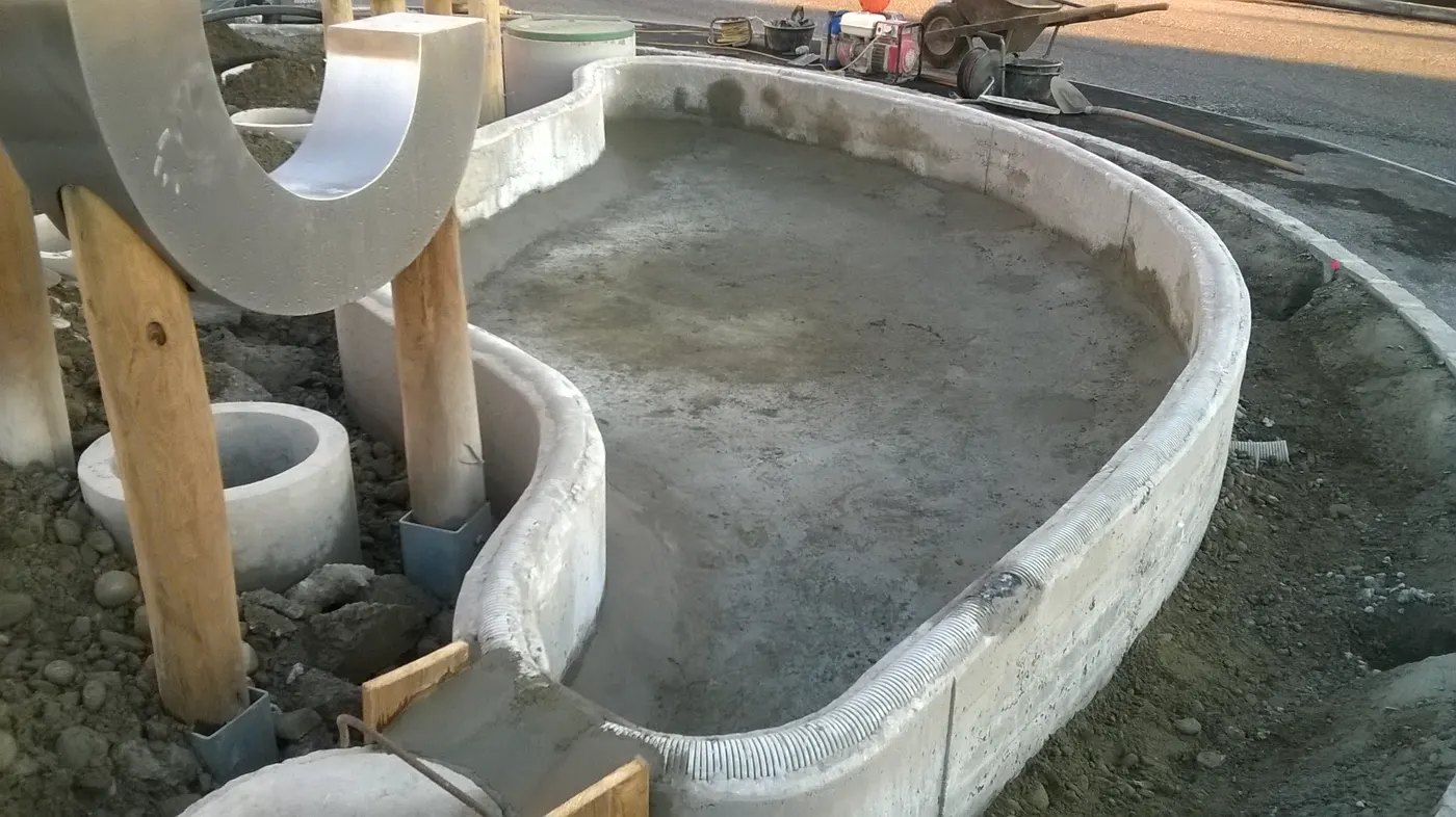 Muro curvo in costruzione attorno al laghetto, con i casseri in legno
